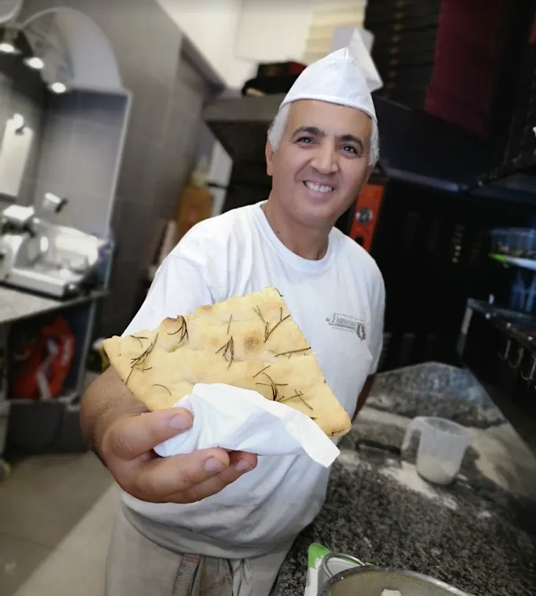 Francesco smiling and holding a slice of rosemary focaccia