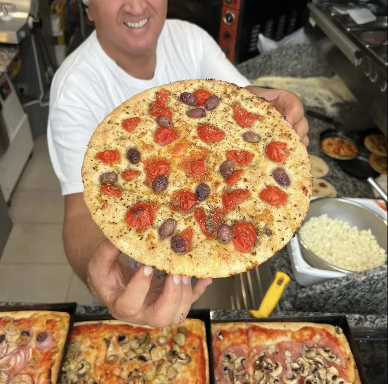 Francesco holding a focaccia with cherry tomatoes and olives