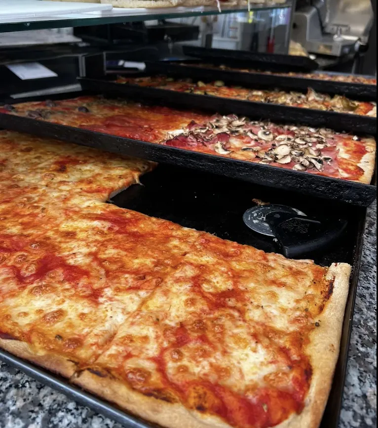 Trays of Roman-style pizza by the slice on the counter