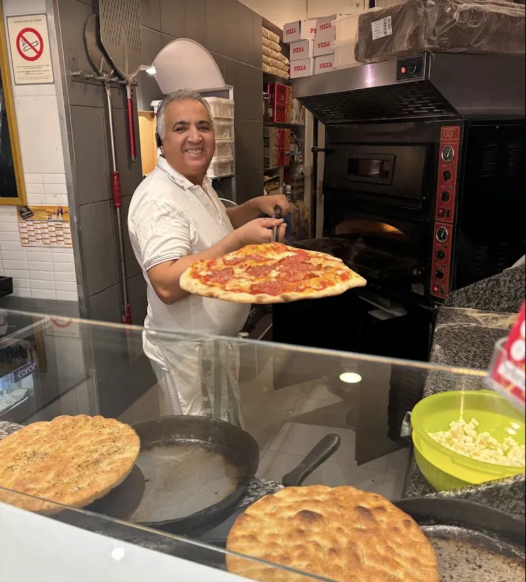 Francesco taking a pizza out of the oven