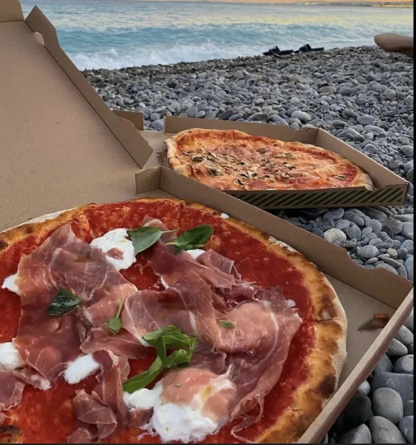 Two Da Francesco pizzas in their boxes on the pebble beach in Nice